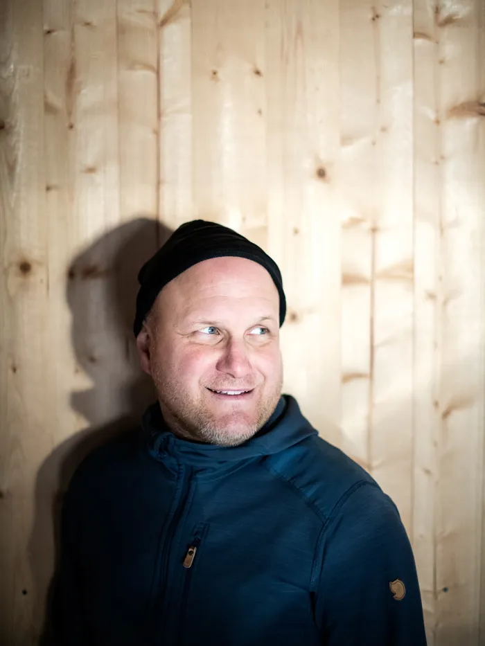 Porträtt av en Fredric Wedin, stående mot en trävägg