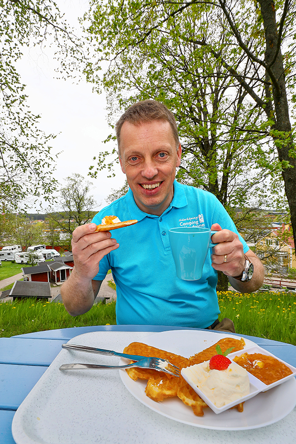 Johan med en kopp kaffe och en våffla på Korskullens café